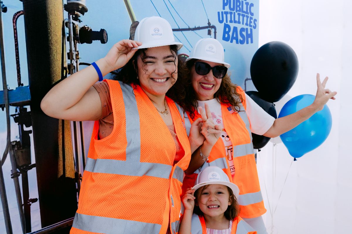 Big Public Utilities Bash attendees pose for a picture with hard hats and safety vests.